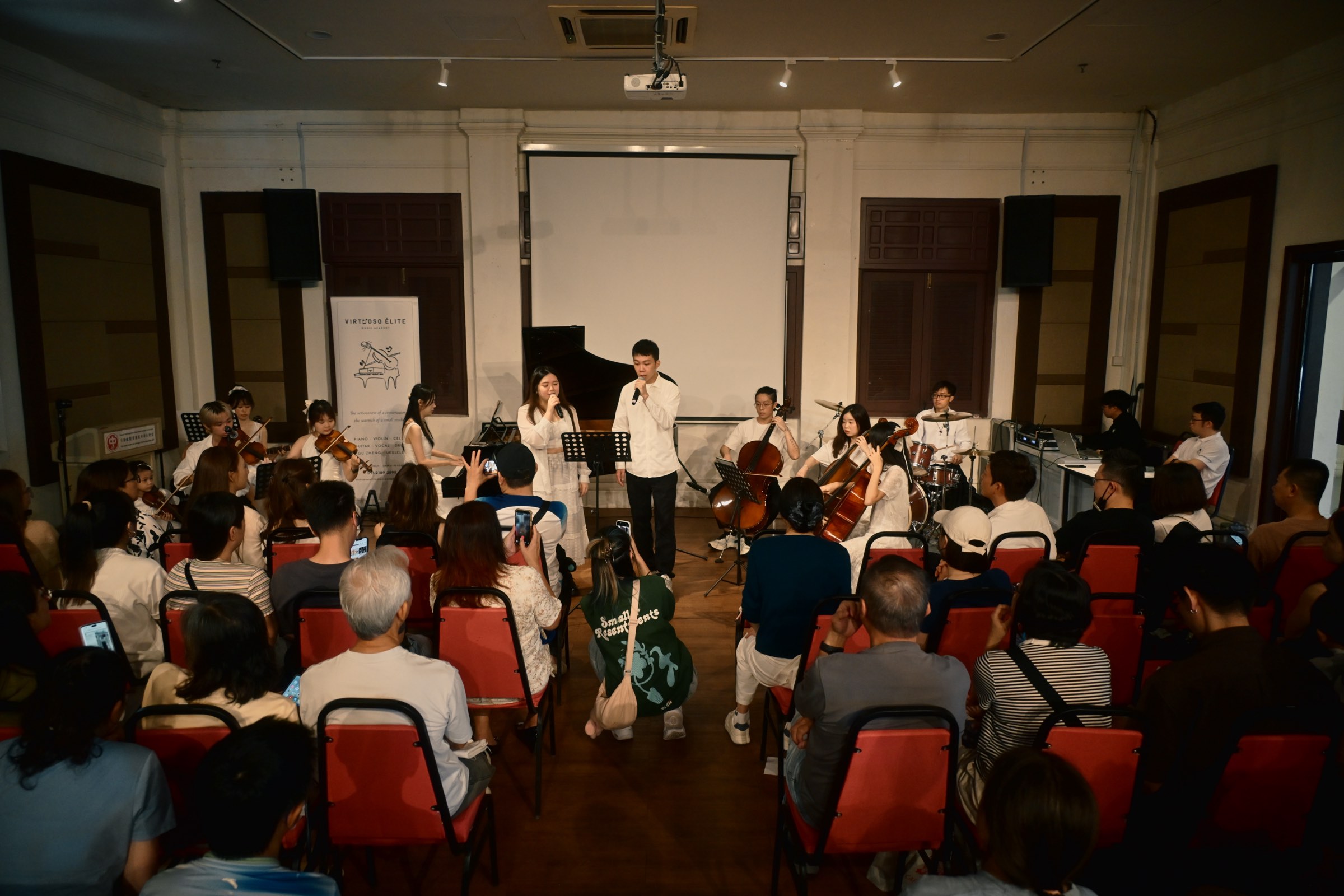 Virtuoso Élite singers, strings, piano and drums performing to a full room at the academy's first annual concert